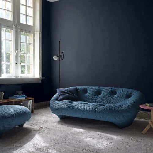 Curved tufted sofa, deep blue walls, Ligne Roset.