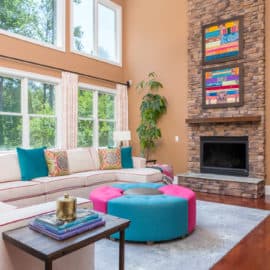interior design living room tall ceilings colorful art custom draperies curtains white sectional sofa couch blue magenta ottoman