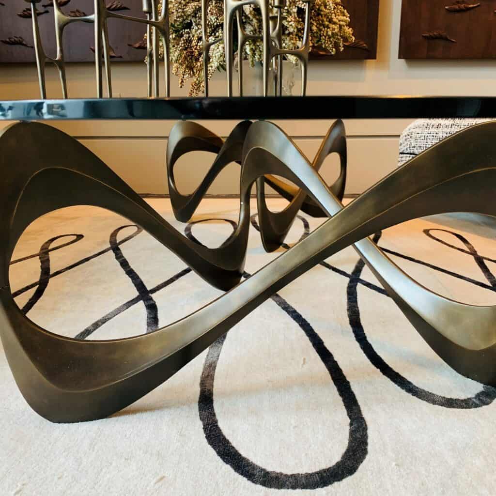 Curved metal base cocktail table. Endless movement.