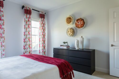 interior design bedroom white bedspread red throw feather wall art custom floral draperies curtains black dresser LK Design