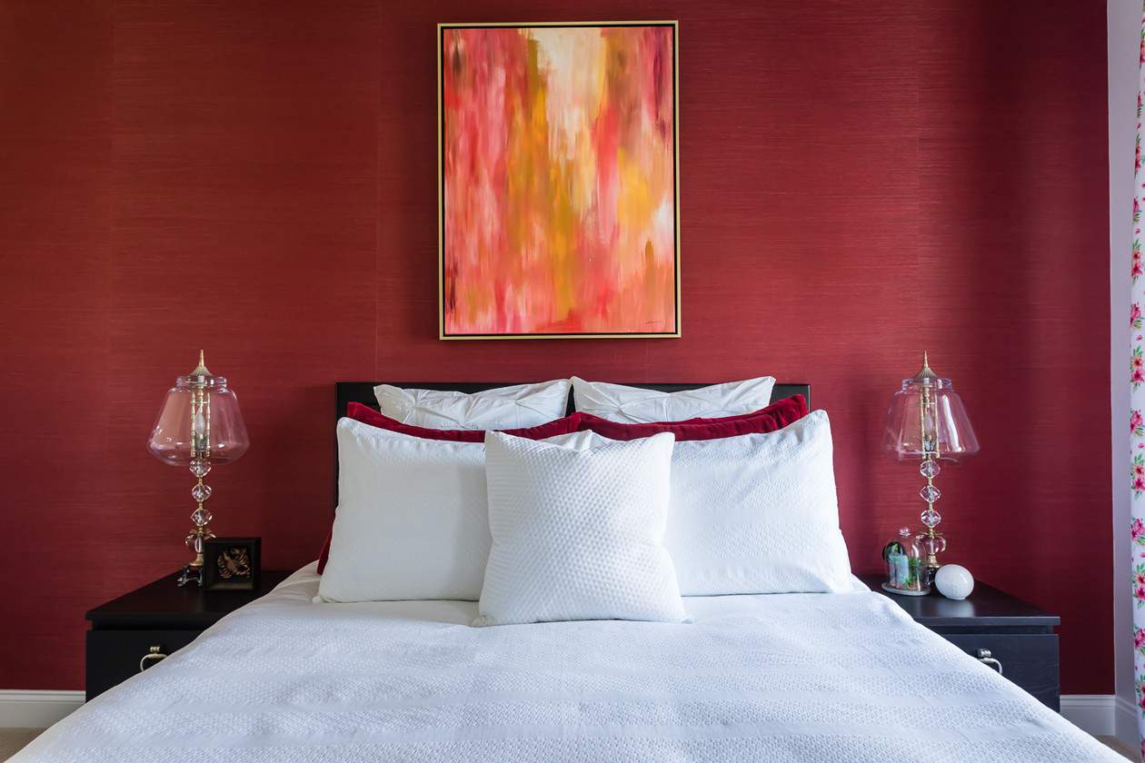 interior design bedroom red wallpaper accent wall yellow gold pink abstract art white bedspread LK Design