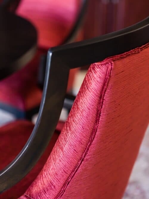 curved red upholstered chair dark wood detail shimmery fabric