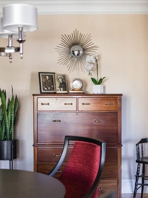 vintage dark wood dresser old photographs red chair potted plant starburst mirror orchid
