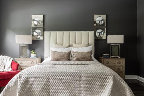 interior design master bedroom gray wall paint beige headboard quilted bedspread red armchair unique lamps