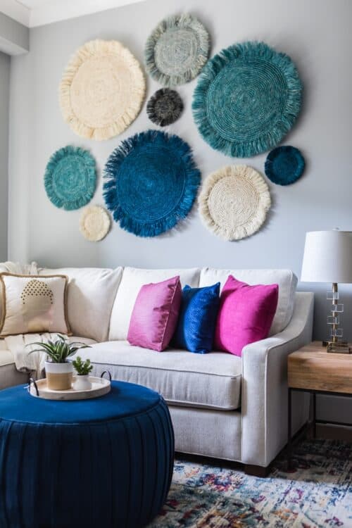 family room white sectional sofa blue magenta pillows colorful rug blue ottoman custom draperies curtains seagrass art potted plants