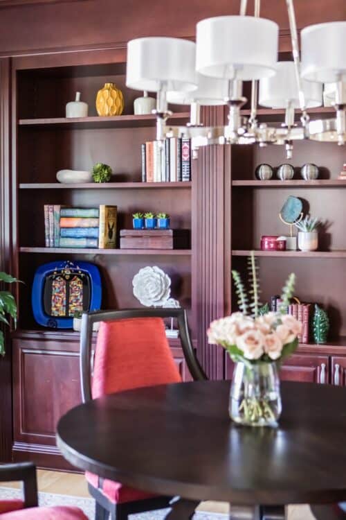 red upholstered chair table bookshelves white chandelier library