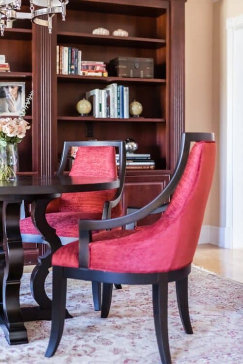 red upholstered chair table bookshelves rug library