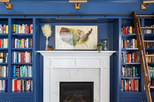 LK Design Home library blue shelves with ladder white fireplace map vases