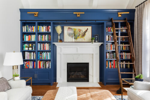 LK Design Home library blue shelves fireplace beige armchair lamp ottoman pillows custom window treatments curtains