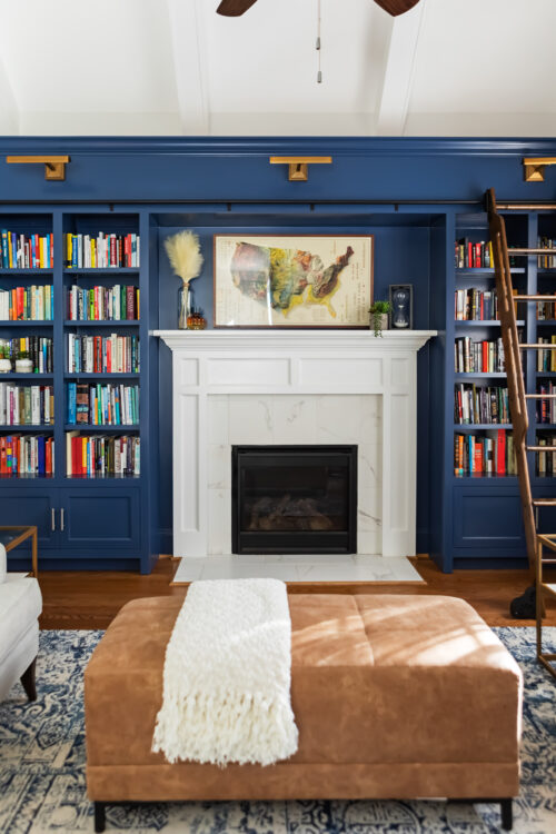 LK Design Home library blue shelves fireplace beige armchair lamp ottoman pillows custom window treatments curtains