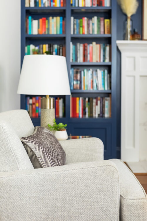 LK Design Home library blue shelves fireplace beige armchair lamp pillow