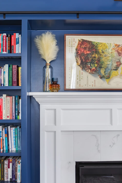 LK Design Home library blue shelves fireplace map vase books