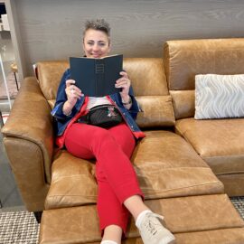 LK Design High PointMarket visit person with a book on reclining sofa